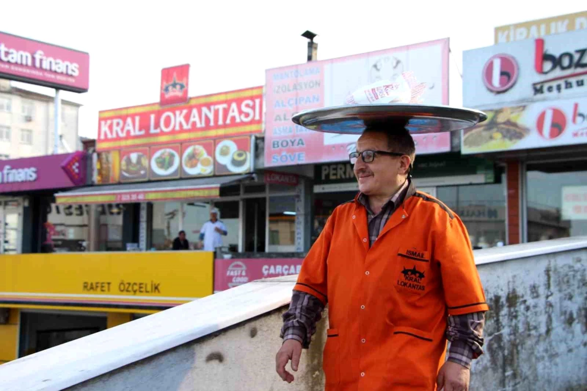 Sipariş verilen yemekleri başında taşıdığı tepsi ile götürüyor